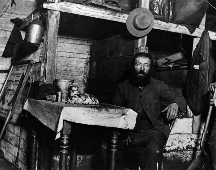 A Jewish cobbler ready for Sabbath Eve in a coal cellar in New York, where he is living with his family. This photograph is one of a series taken of New York's slums, using the newly invented technique of flashlight photography. (Photo by Jacob A Riis/Getty Images)