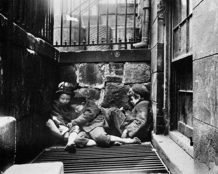 Three young street arabs huddle together for warmth in an areaway, Mulberry St, New York. (Photo by Jacob A Riis/Getty Images)
